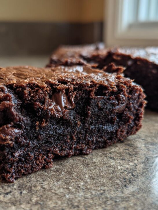 Close-up of a fudgy zucchini chocolate brownie, showing rich chocolate chips and a moist crumb.