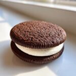 A close-up, appetizing photo of a homemade Chocolate Sandwich Cookies with thick white cream filling.