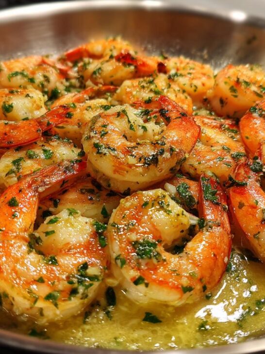Close-up of Irresistible Garlic Butter Shrimp cooked in a pan with melted butter and parsley.