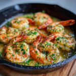 Close-up of Irresistible Garlic Butter Shrimp cooked in a cast-iron skillet, garnished with parsley.