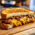 Close-up of an Irresistible Grilled Cheese Sloppy Joes sandwich with melted cheese oozing out.