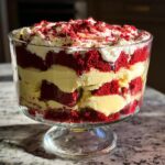A close-up of an Irresistible Red Velvet Cheesecake Trifle in a glass bowl, layered with red velvet cake, cream cheese filling, and whipped cream.