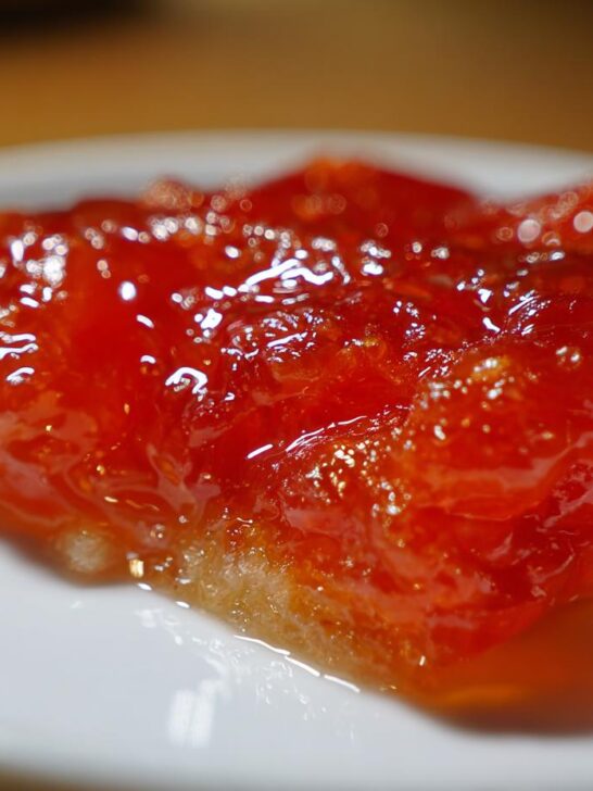 Close-up of a glistening, vibrant orange sweet and sour sauce glaze on a white plate.