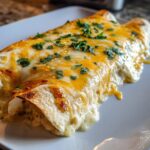 Close-up of Irresistible White Chicken Enchiladas covered in melted cheese and fresh cilantro.