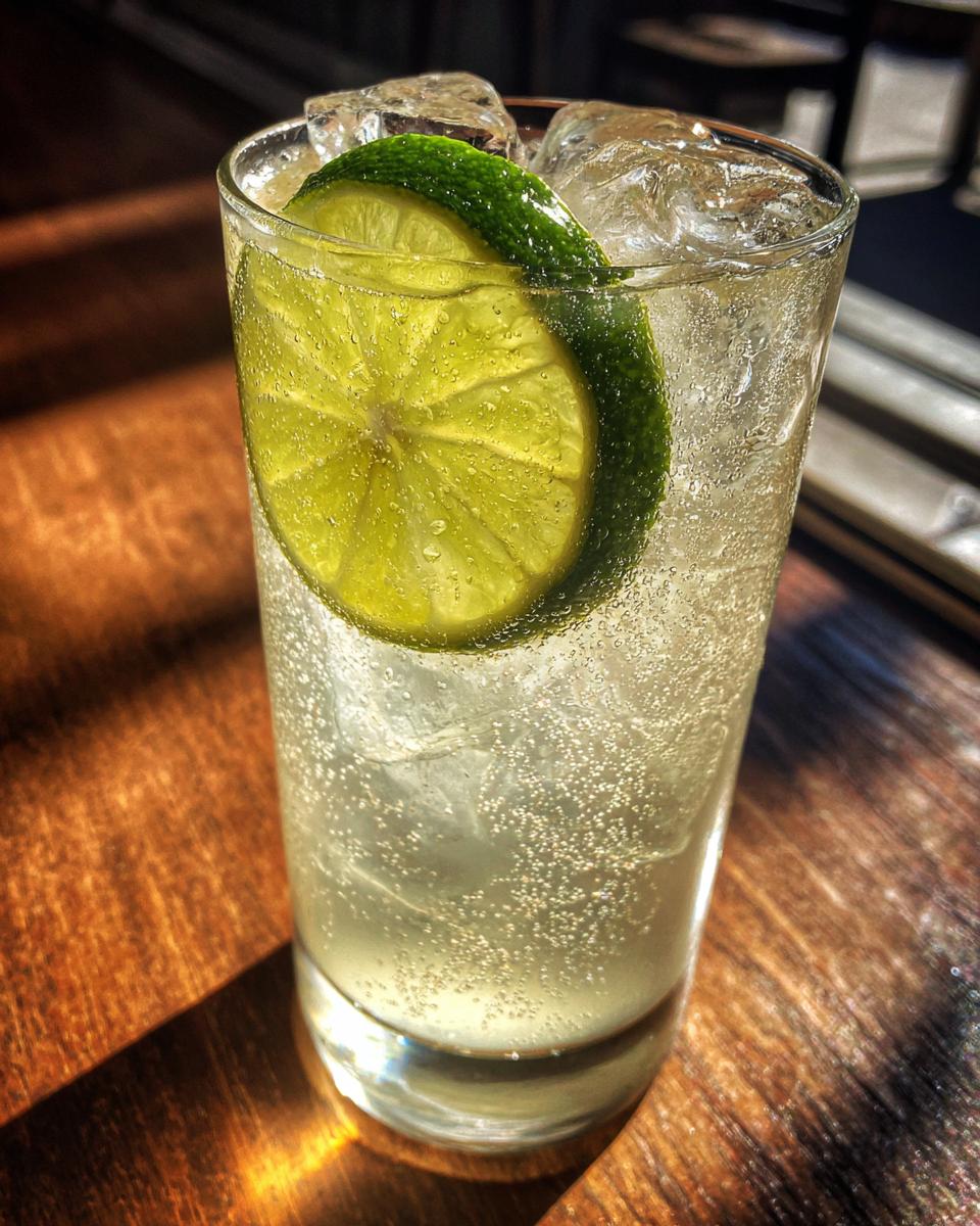 A refreshing Kansas City Ice Water Cocktail in a tall glass, filled with ice and garnished with lime slices.