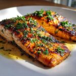 Two perfectly cooked Lemon Butter Grilled Salmon fillets, glistening with sauce and topped with fresh parsley.