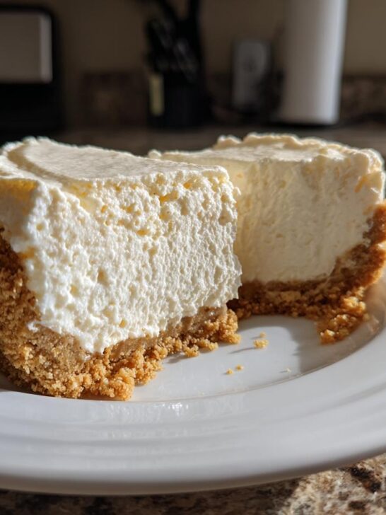 Two thick slices of creamy No Bake Cheesecake on a white plate, showing the graham cracker crust.