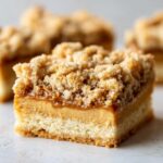A close-up cross-section of a delicious Peanut Butter Shortbread Bars square showing the shortbread base, creamy filling, and crumb topping.