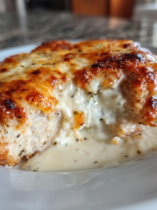 A close-up of a juicy Ranch Pork Chop recipe, topped with melted golden-brown cheese and a creamy ranch sauce.
