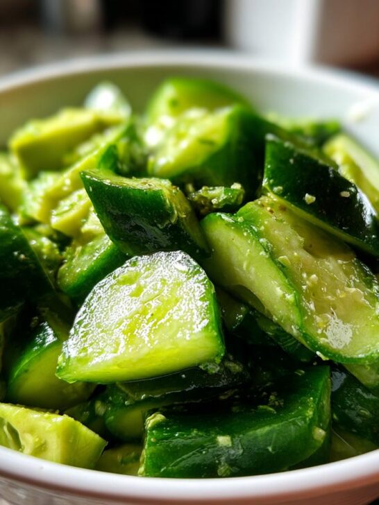 A close-up of a Refreshing Cucumber Avocado Salad Recipe in a white bowl, showcasing vibrant green chopped cucumbers and creamy avocado chunks.