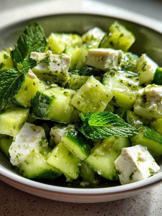 A close-up of a Refreshing Cucumber Feta Salad with chunks of cucumber, feta cheese, and fresh mint leaves.