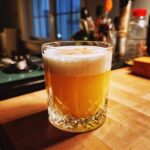 A perfectly crafted Scotch Sour cocktail with a frothy top, garnished with a sprinkle of spice, in a crystal glass.