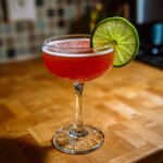 A vibrant red Siesta Cocktail in a coupe glass, garnished with a lime wheel, perfect for a quick recipe.