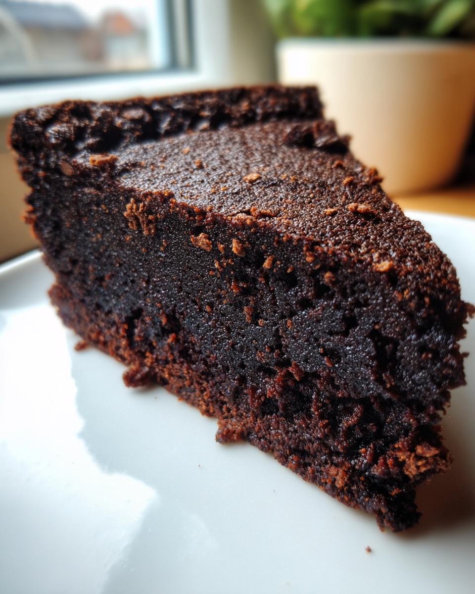 Close-up of a dense, dark slice of Chocolate Biscuit Cake served on a white plate.