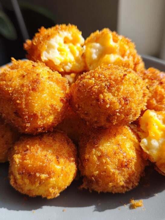 A pile of golden-brown, crispy Irresistible Texas Roadhouse Rattlesnake Bites on a gray plate, some with gooey cheese centers visible.