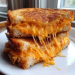 Close-up of a perfectly toasted Air Fryer Grilled Cheese sandwich cut in half, showing dramatic, gooey, melted cheese strings.