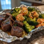 Close-up of cooked steak medallions, shrimp, and broccoli inside a foil pack for Surf And Turf Foil Packs.