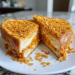 A thick slice of Baked Crunch Cinnamon French Toast, coated in crunchy cereal, cut in half to show the creamy filling.