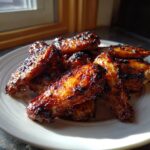 Close-up of glossy, caramelized Baked Jamaican Jerk Chicken Wings piled on a white plate.