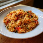 Close-up of creamy BBQ Jerk Lobster Garlic Herb Orzo garnished with fresh parsley in a white bowl.