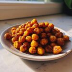 A close-up of perfectly crispy, golden brown roasted chickpeas piled high on a small white plate.