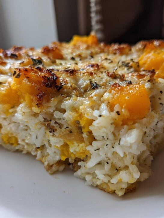 Close-up of a square slice of Butternut Squash And Rice Casserole with a cheesy, browned top.