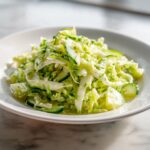Close-up of a bright, refreshing Cabbage Cucumber Salad tossed in a light vinaigrette, served in a white bowl.