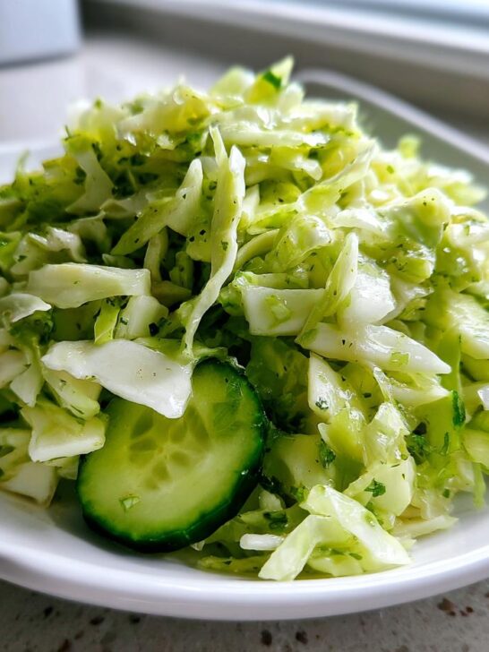 A close-up of a vibrant Cabbage Cucumber Salad featuring shredded cabbage and sliced cucumbers dressed lightly.