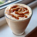 Close-up of a thick Caramel Banana Smoothie topped with a swirl of rich caramel sauce.