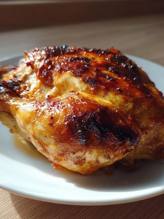 A piece of juicy, roasted Chicken In A Pot with deeply browned, crispy skin served on a white plate.