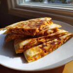 Stack of golden-brown quesadilla wedges filled with shredded chipotle chicken, ready to eat.