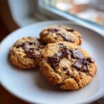 Three delicious Chocolate Chip Cookies Keto, topped with large chocolate chunks and sea salt, resting on a white plate.