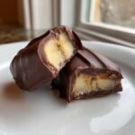Two halves of a Chocolate Covered Frozen Bananas treat showing the frozen banana interior coated in dark chocolate.