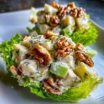 Close-up of Classic Waldorf Salad served in lettuce cups, topped generously with walnuts.