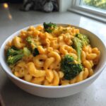 A white bowl filled with creamy, orange Copycat Velveeta Broccoli Mac Cheese and elbow macaroni.