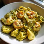 Close-up of Creamy Shrimp Pesto Tortellini Pasta tossed in a rich green sauce and topped with seasoned shrimp.