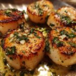 Close-up of perfectly seared Garlic Butter Scallops topped with minced garlic and fresh parsley in butter sauce.