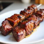 Close-up of perfectly grilled Asian Beef Skewers, glistening with a rich glaze, served on a white plate.