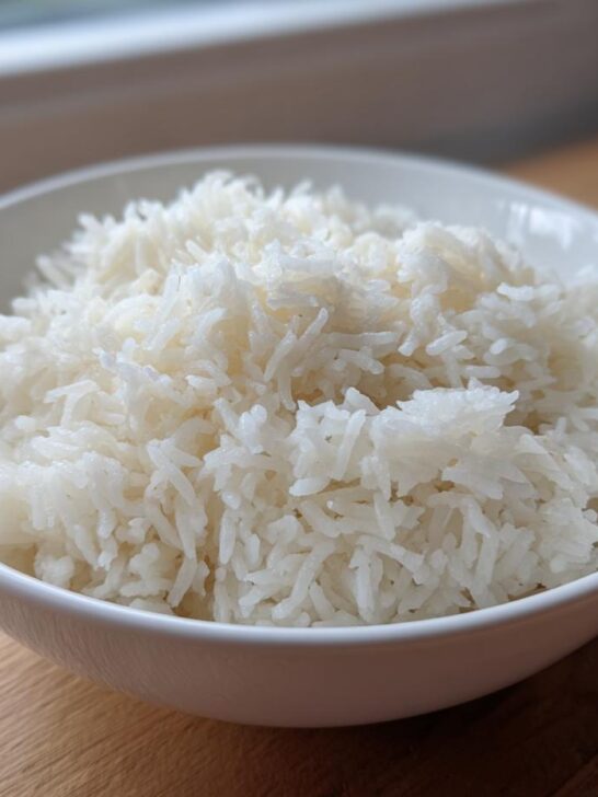 A close-up of a white bowl filled with perfectly fluffy, cooked Basmati rice, ready to serve.