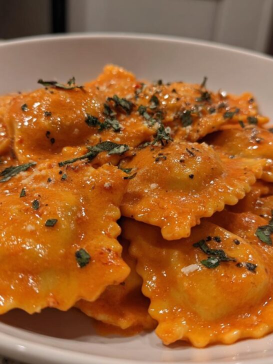 Close-up of Hubbys Date Night Vodka Ravioli coated in a rich, orange-hued cream sauce and sprinkled with herbs.