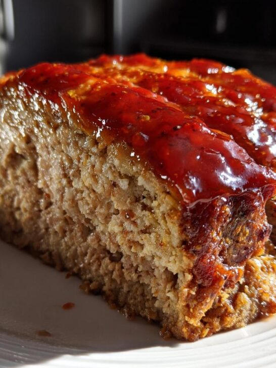 Close-up of a thick slice of juicy Instant Pot Meatloaf topped with a shiny, dark red glaze.