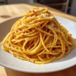 A close-up of perfectly twirled Lemon Brown Butter Spaghetti topped with grated cheese and lemon zest.