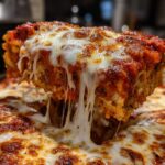 A close-up shot showing a lifted slice of Meatless Baked Ziti With Ricotta Mozzarella with dramatic cheese pulls.