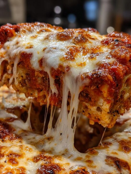 A close-up shot showing a lifted slice of Meatless Baked Ziti With Ricotta Mozzarella with dramatic cheese pulls.