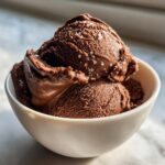 Two scoops of rich, dark brown Mocha Latte Frozen Yogurt sprinkled with sea salt in a white bowl.