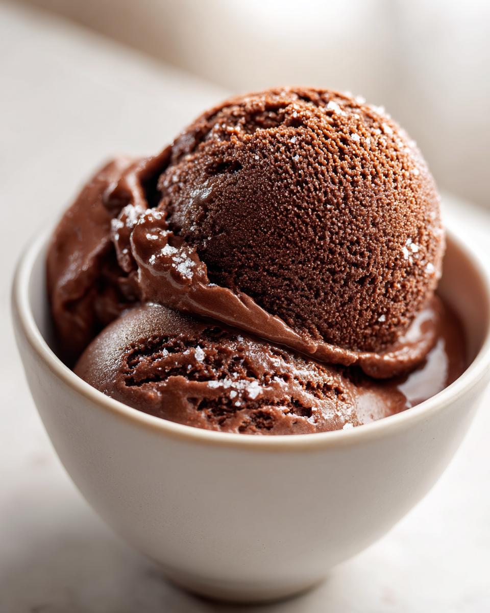 Close-up of rich, dark brown Mocha Latte Frozen Yogurt scoops sprinkled with sea salt in a light bowl.