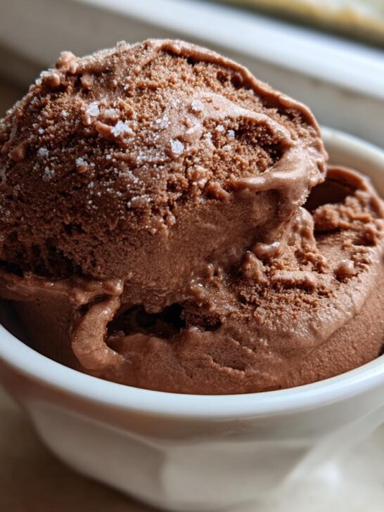 Two scoops of rich, dark brown Mocha Latte Frozen Yogurt dusted with fine sugar crystals in a white bowl.