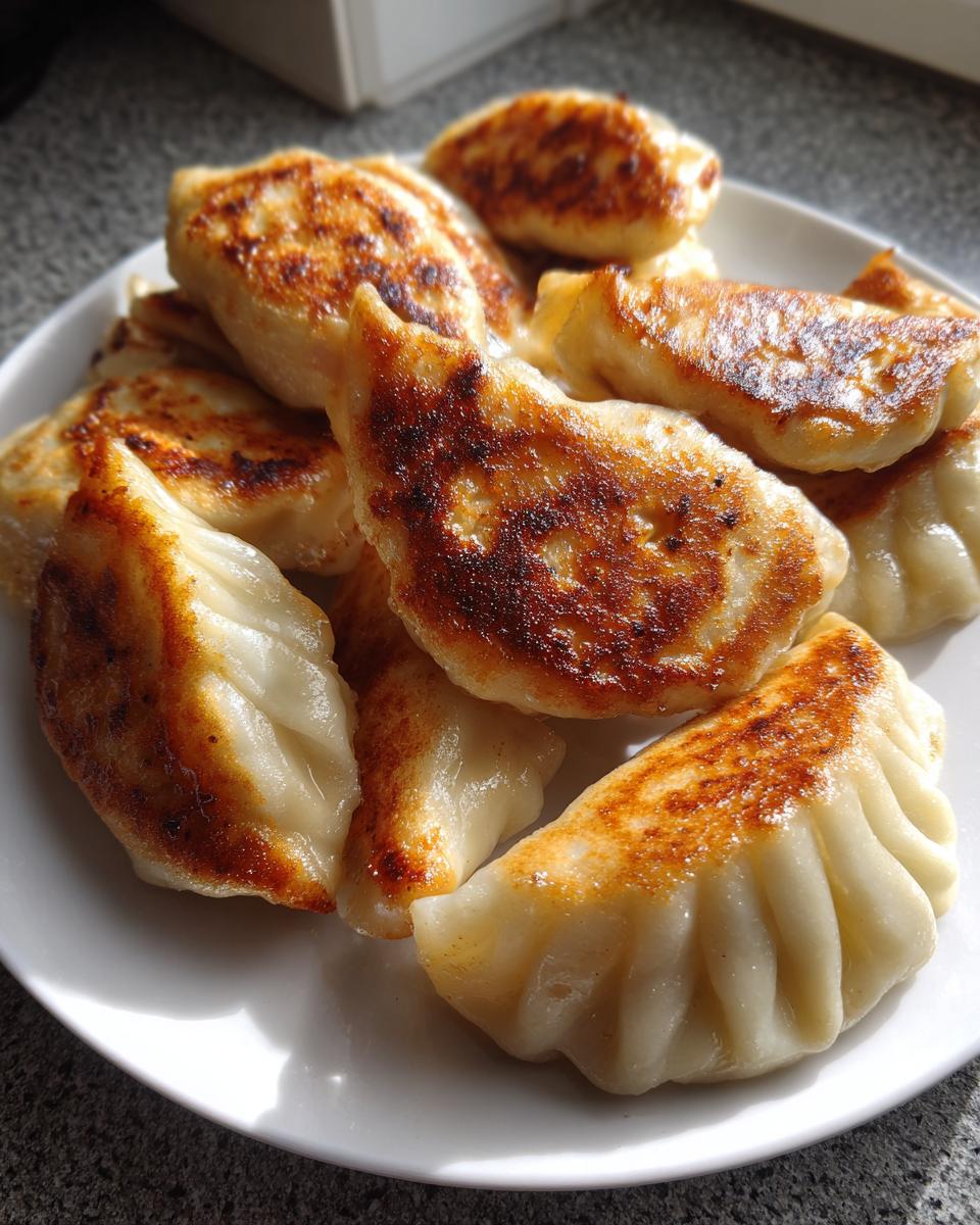 A pile of golden-brown, pan-fried Jerk Chicken Dumplings served on a white plate.