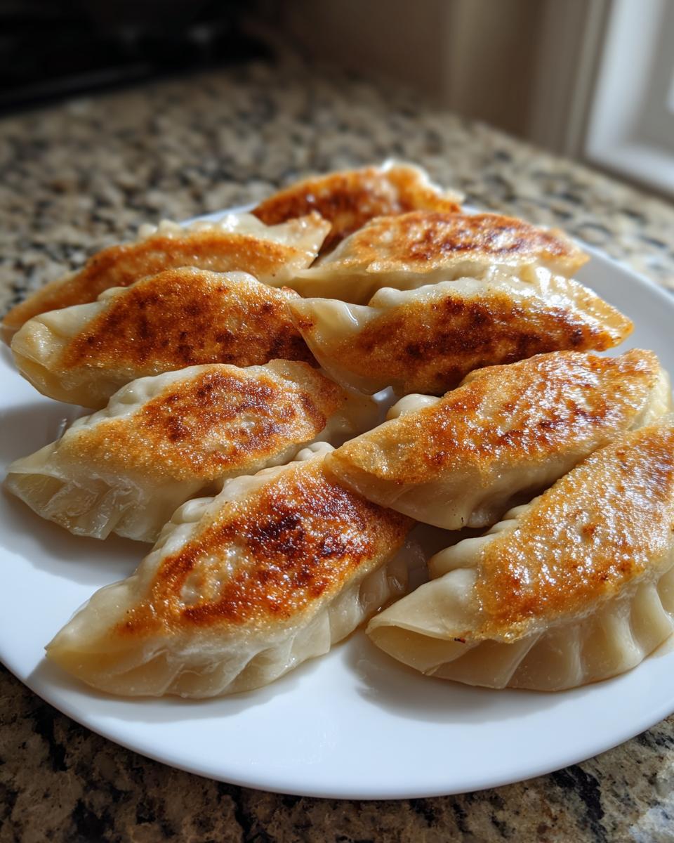 Close-up of several golden-brown, pan-fried Jerk Chicken Dumplings arranged on a white plate.