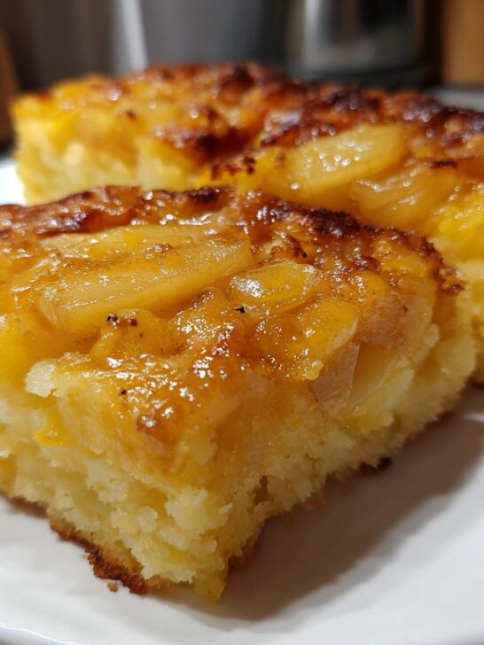 Two golden slices of Polenta Cakes With Apples And Cheddar served on a white plate, featuring a caramelized apple topping.